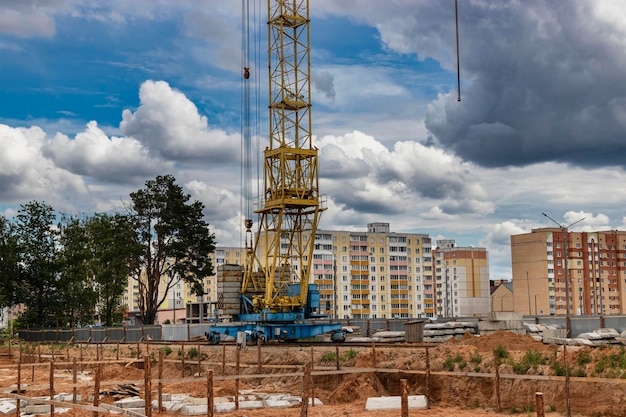 A large tower crane at a construction site against the backdrop of a modern monolithic house Modern housing construction industrial engineering Construction of mortgage housing