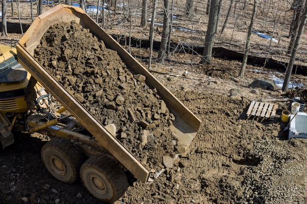 A large track articulating dump truck unloading of rock and soil at a new road under construction project