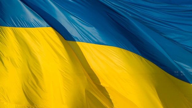 Large Ukrainian flag, made of high quality material, flutters in the wind, creating waves.