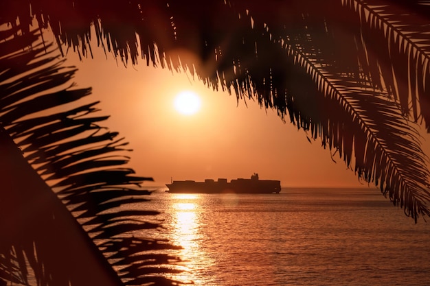 A large vessel on horizon in the atlantic ocean under the bright sun and red sunset Sunlight reflection off the water