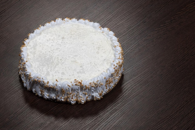 Large white cake with a blank top on a wooden table