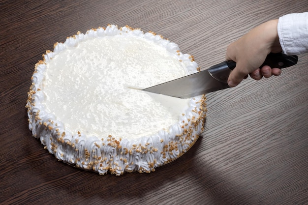 Large white cake with a clank top is cut with a knife