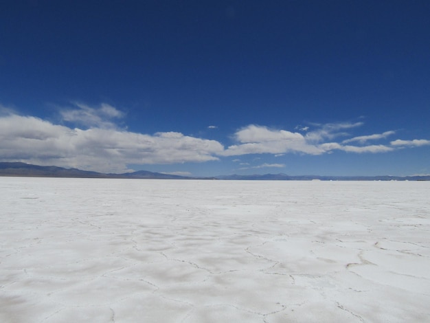 A large white salt flat with a mountain in the background.