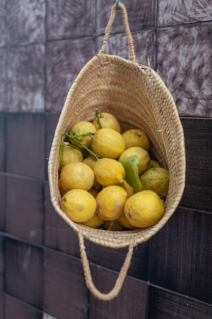 Large wicker basket with lemons hangs on a hook on the wall