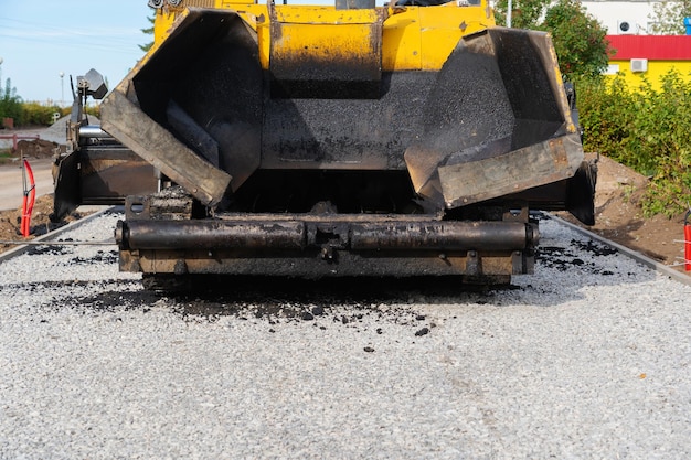 Large yellow asphalt paving machine rear view of an empty asphalt hopper