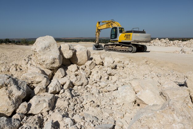 Photo a large yellow tracked excavator is mining rock in a quarry.