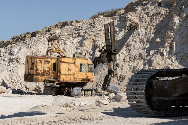 Photo a large yellow tracked excavator is mining rock in a quarry.