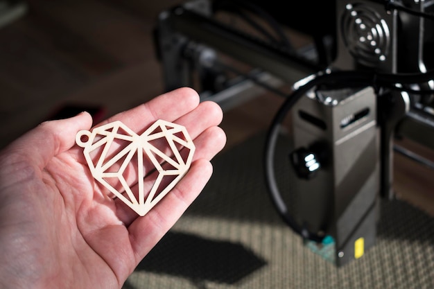 Laser engraving and cutting hand holding an example of a cut out wooden heart