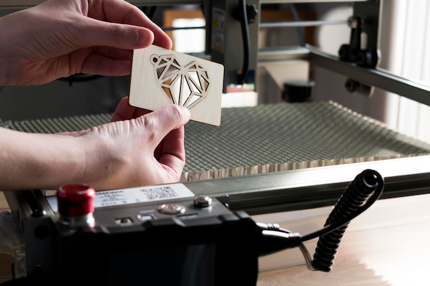 Laser engraving and cutting woman holding an example of a cut out wooden heart