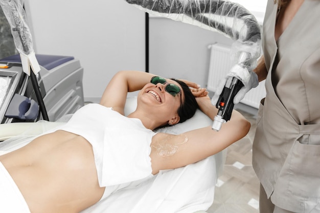 Laser hair removal process woman during laser hair removal of armpits and underarms in beauty center