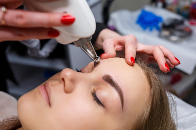 Laser removal of permanent makeup on the face. Close-up of a young woman getting tattoo correction. Correction of natural imperfections on the face.