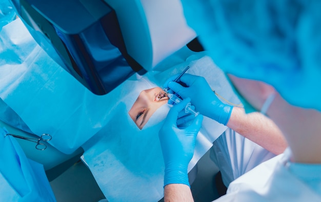 Laser vision correction. A patient and team of surgeons in the operating room during ophthalmic surgery. Eyelid speculum. Lasik treatment.