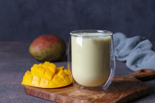 Lassi Mango in glass on wooden board on dark gray background Indian healthy ayurvedic cold drink with mango