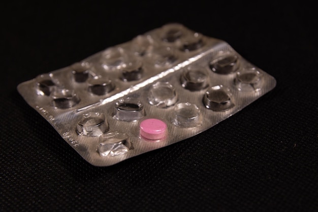 Last antibiotic pill in blister pack on a black background Healthcare and medicine concept