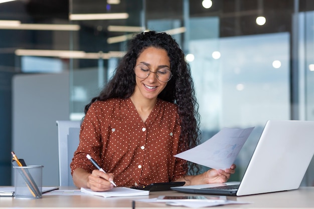 Latin american businesswoman working inside office with documents and laptop worker paperwork