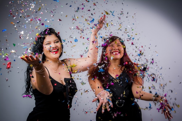 Latin American girls posing and celebrating the new year with balloons and confetti