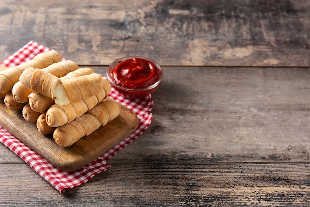 Latin American tequeos stuffed with cheese on wooden table