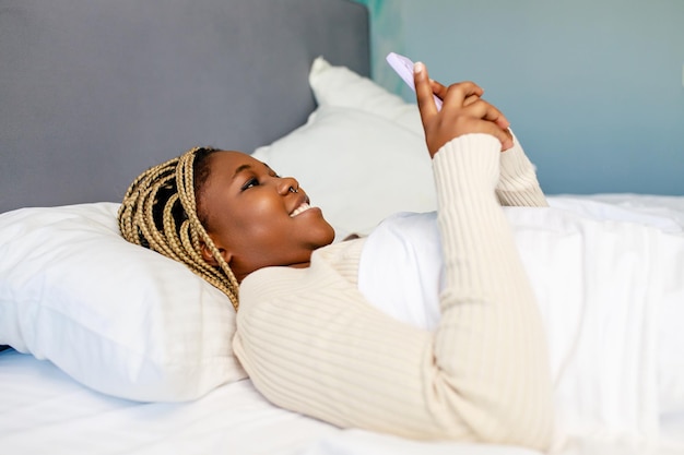 Latin american woman using phone after awake in bed