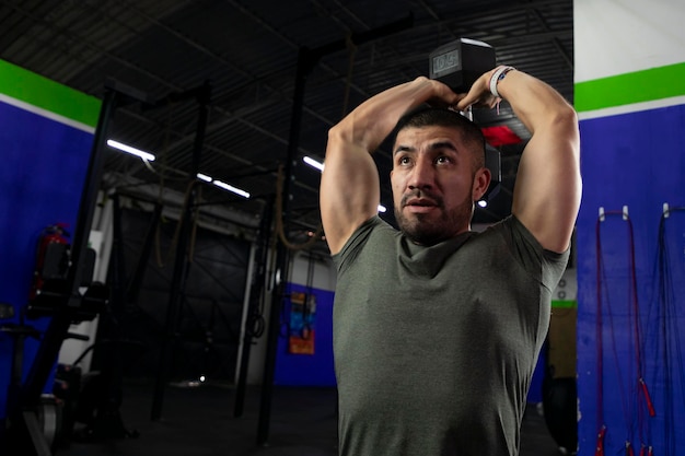 Latin athlete doing triceps exercise in a gym with a dumbbell