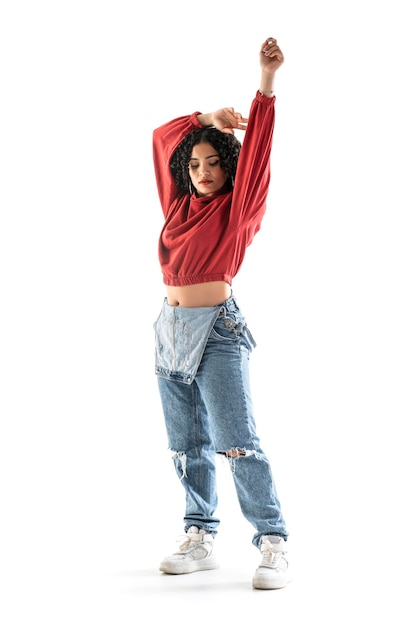 Latin brunette woman with curly hair is dancing in studio with white background