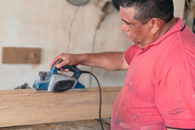 Latin carpenter in wood workshop surrounded by tools