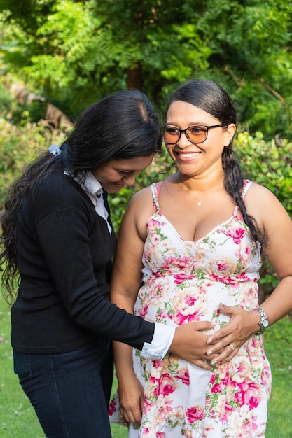 Latin daughter holds her mother39s hands on her pregnant belly