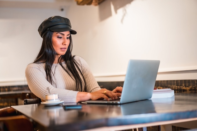 Latin fashion designer making some designs in a cafeteria with her laptop