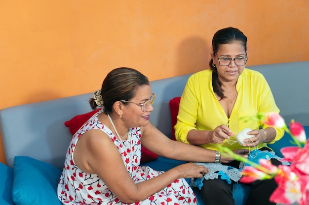 Latin female friends hanging out at home using cell phone.