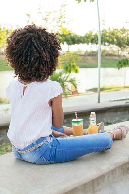 Latin Girl eating vegetables while sitting in a park