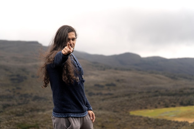 latin male traveler with long hair and beard pointing to the viewer