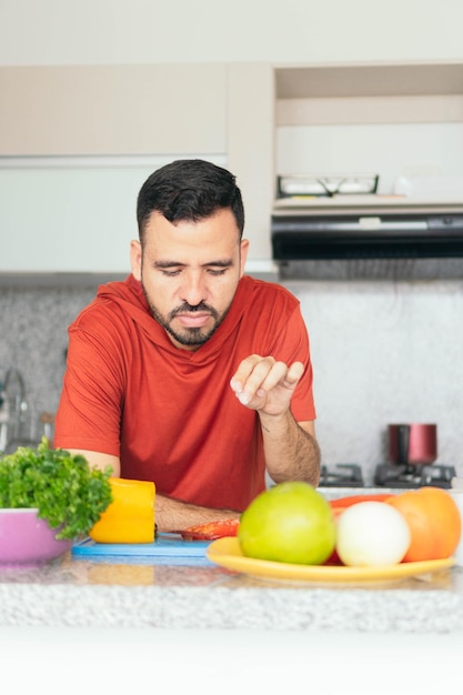 Latin man cooking a healthy salad of fruits and vegetables