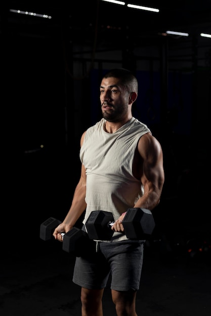 Latin man doing biceps work in the gym with two dumbbells