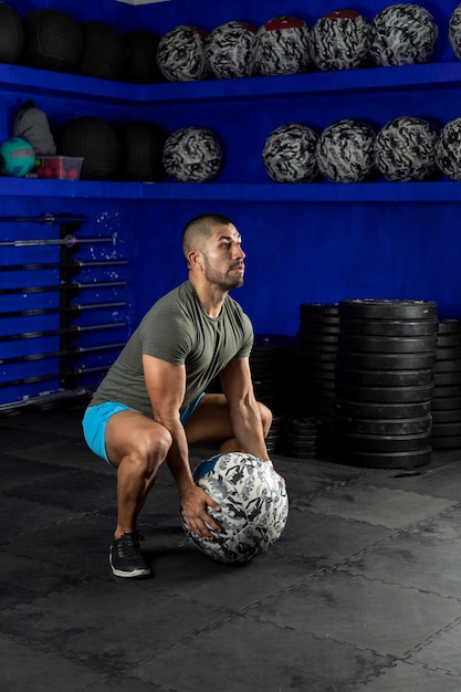 Latin man exercising in a gym using a crossfit medicine ball