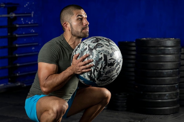 Latin man exercising in a gym using a crossfit medicine ball