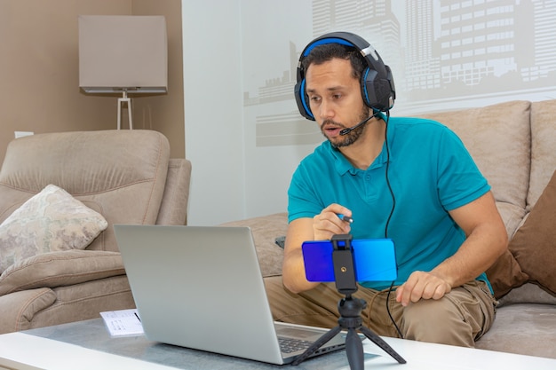 Latin man taking an online course from the sofa of his home (concept of online course and higher education)