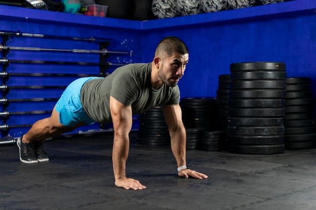 Latin man with sportswear doing high plank in a crossfit gym