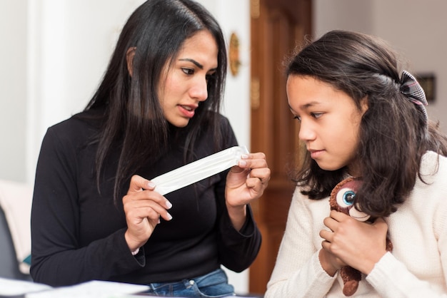 Latin mother shows the stick she has to insert to her daughter to perform the auto test at home