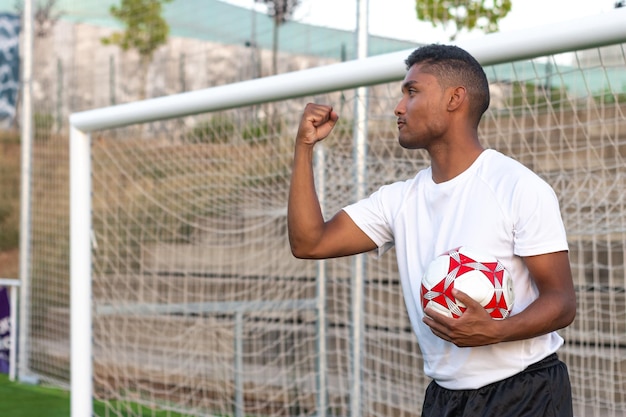 Latin soccer player with ball in hand celebrating a goal Concept of a player celebrating a goal with the ball in hand