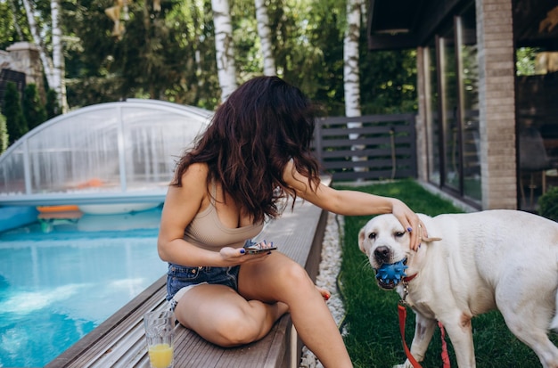 Latin woman by a pool with a retriever dog at sunset portrait