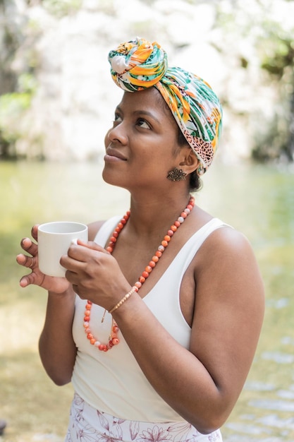 Latin Woman enjoying morning coffee by the river