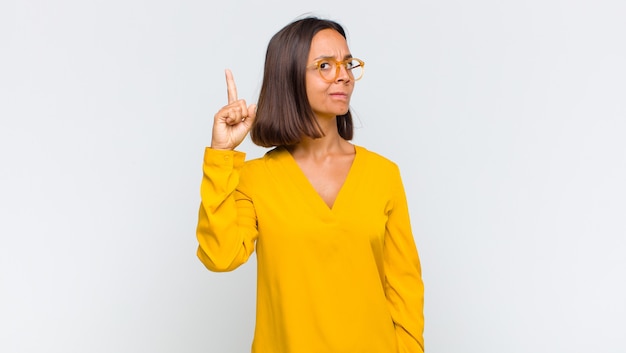 Latin woman feeling like a genius holding finger proudly up in the air after realizing a great idea, saying eureka