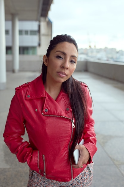 Latin woman in red jacket looking at camera.