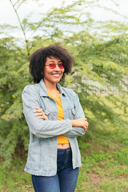 Latin woman smile while posing with her arms crossed on a green natural background