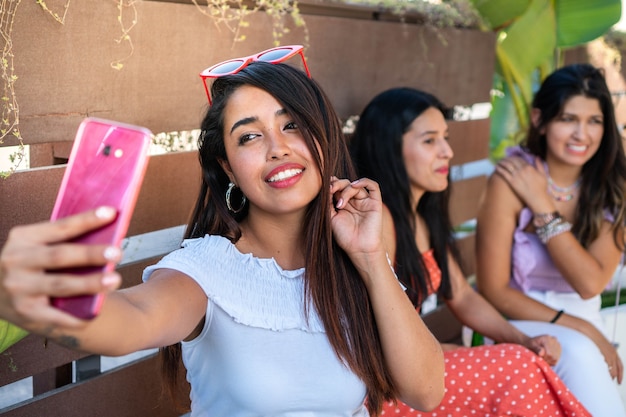 Latin woman taking a selfie with her friends Hispanic girl with a nice smile takes a photo