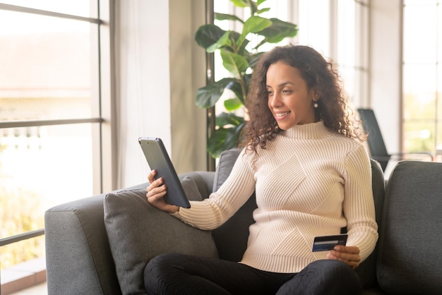 Latin woman using tablet and hand holding credit card - Online shopping concept