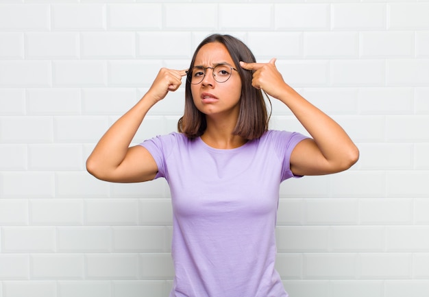 Latin woman with a serious and concentrated look, brainstorming and thinking about a challenging problem