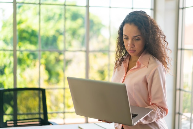 Latin woman working with laptop on working space at home