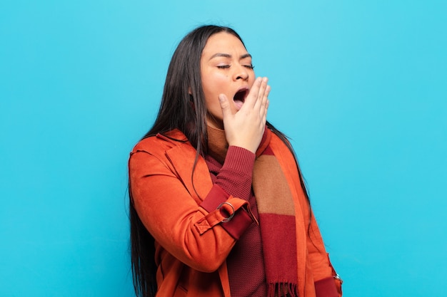 latin woman yawning lazily early in the morning, waking and looking sleepy, tired and bored