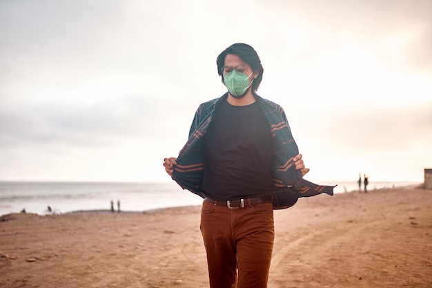 Latin young man poses walking on the sand during a beautiful sunset