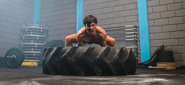 Latin young man working out with a tractor tire at a crossfit gym